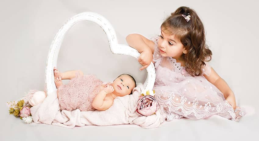 Familienfoto mit Schwester die ihr süßes Babyschwesterchen bestaunt beim Fotoshooting in Wuppertal