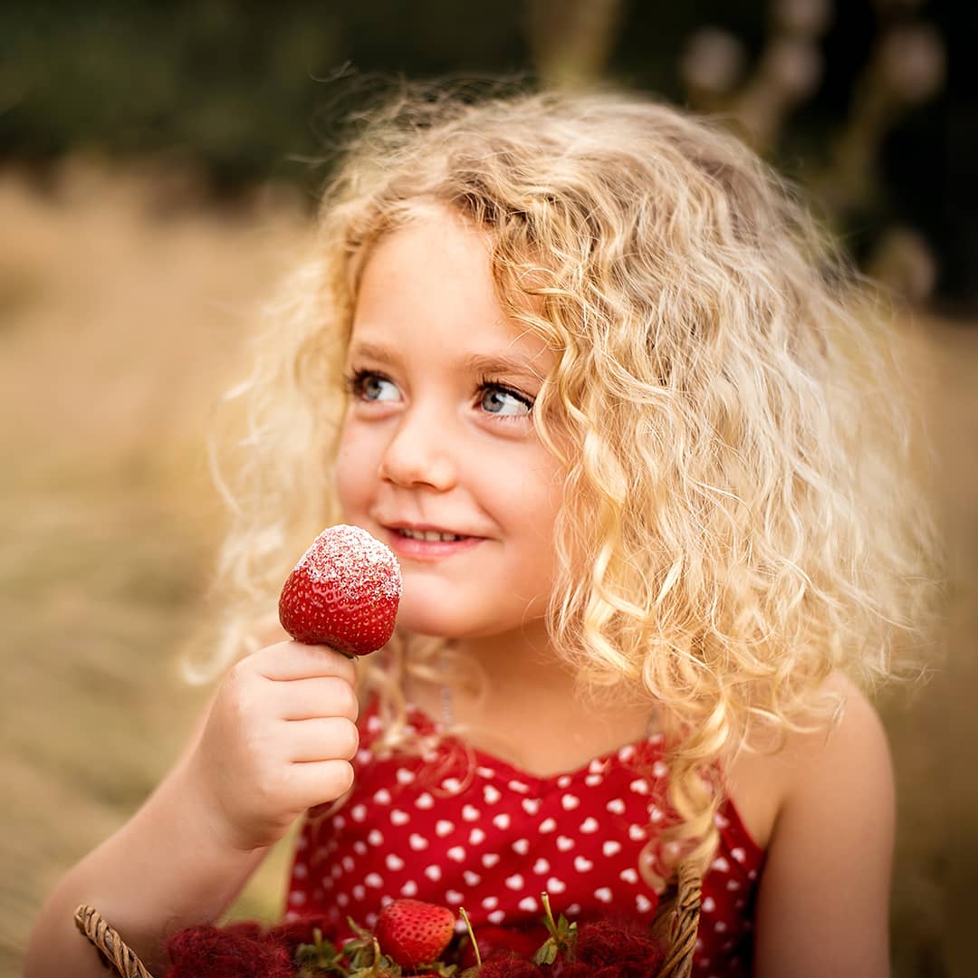 Glückliches Kind nascht Erdbeeren beim kreativen Outdoor-Abenteuer-Fotoshooting für Familien und Kinder im Raum Wuppertal