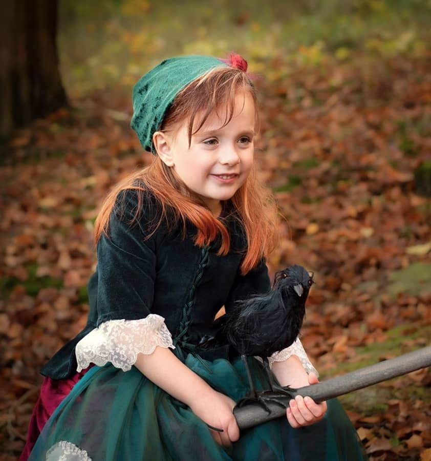 Kleines Mädchen bei einem Märchenfotoshooting als kleine Hexe auf einem Hexenbesen mit Abraxas dem Raben